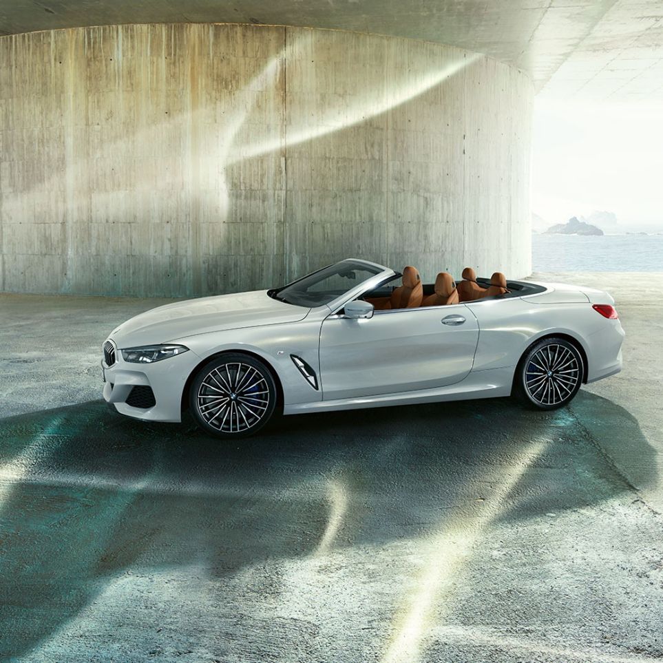 BMW M850i xDrive in Mineral White metallic, side view with soft top open. BMW M850i xDrive in Mineral White metallic, side view with soft top open.