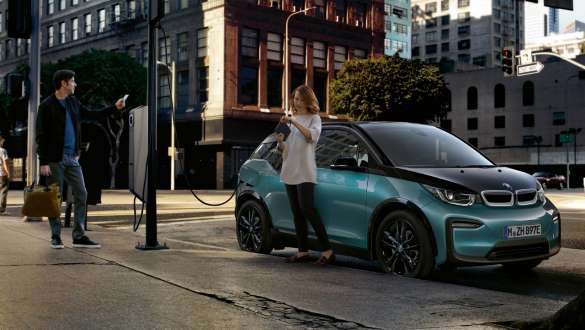 Couple charging their BMW i3 at a public charging station I01 2018 Blue Ridge Mountain with Frozen Grey metallic highlight