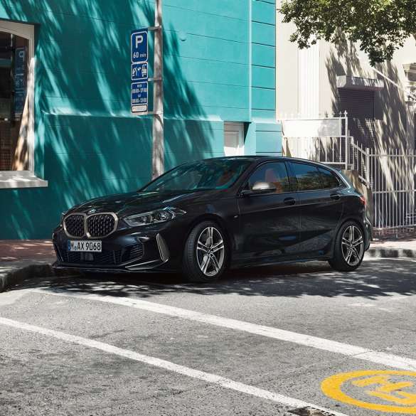 BMW M135i xDrive, three-quarter side view. The all-new BMW M135i xDrive in Black Sapphire metallic, three-quarter side view parking.