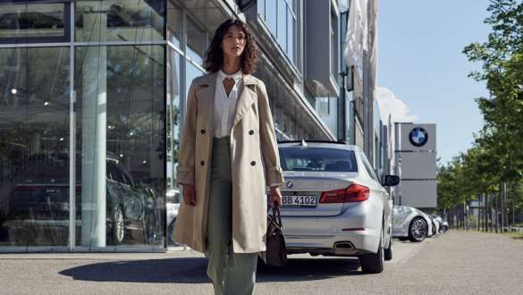 Woman in front of BMW car dealership BMW Service Inclusive Woman in front of BMW car dealership