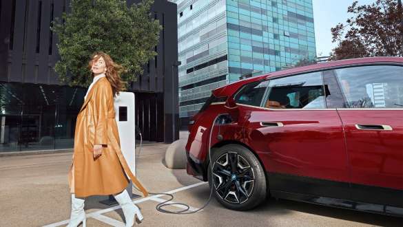 Charging solutions for employers Woman in front of BMW iX at charging station