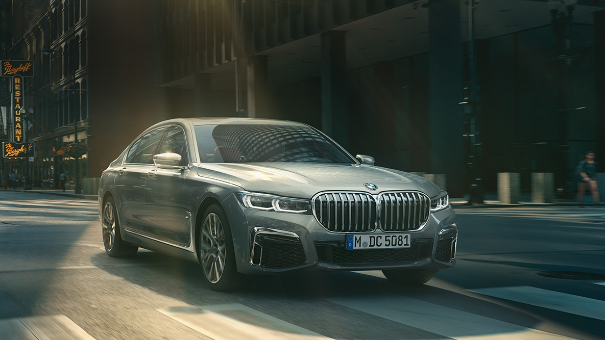 BMW 7 Series Sedan Driving Assistant Professional Driving Assistant Professional: three-quarter front view of BMW 7 Series Sedan driving in front of urban setting