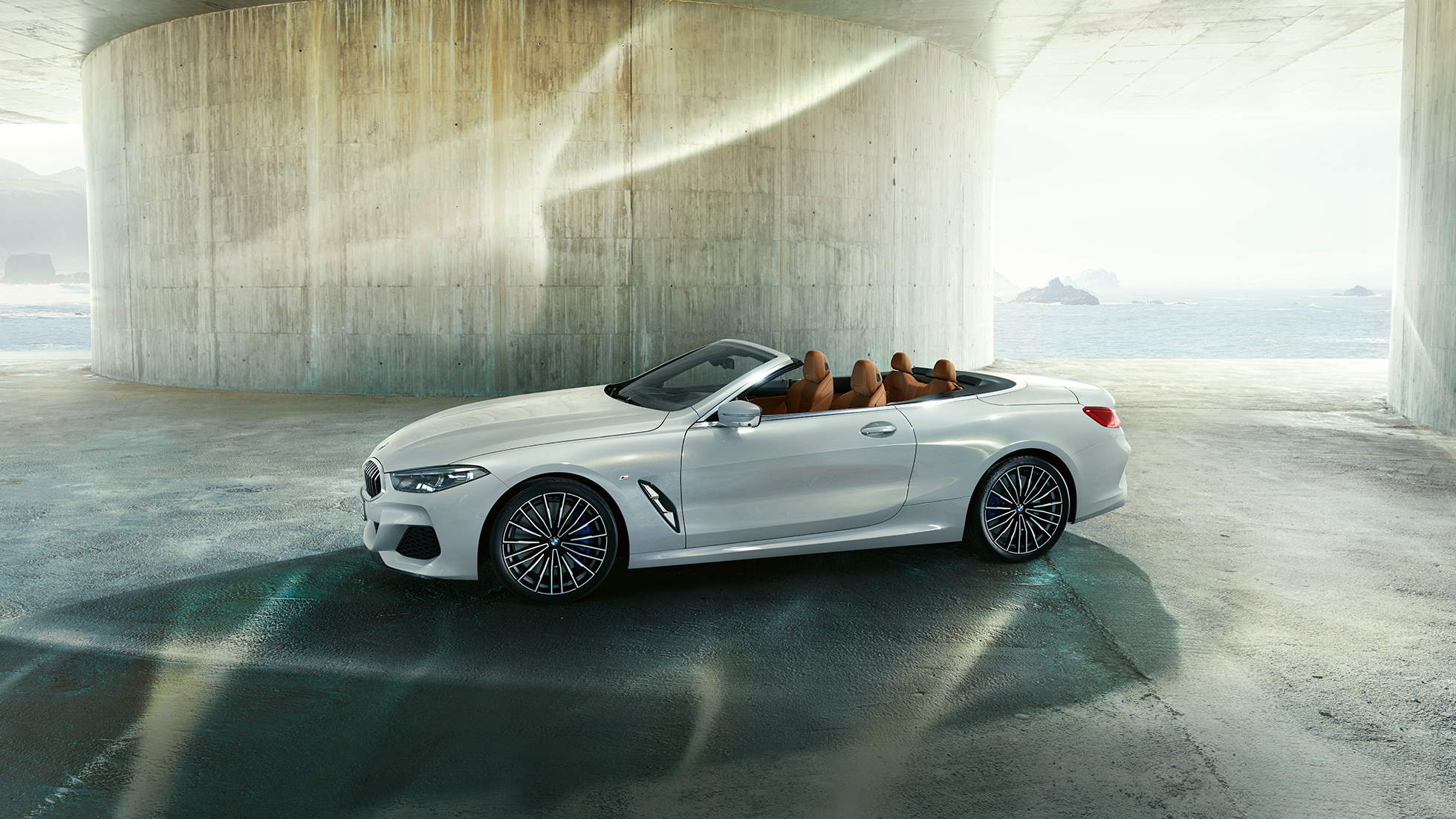 BMW M850i xDrive in Mineral White metallic, side view with soft top open. BMW M850i xDrive in Mineral White metallic, side view with soft top open.