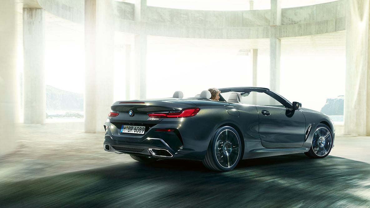 BMW M850i xDrive with soft top open, driving, side view. BMW M850i xDrive with soft top open, driving, side view.