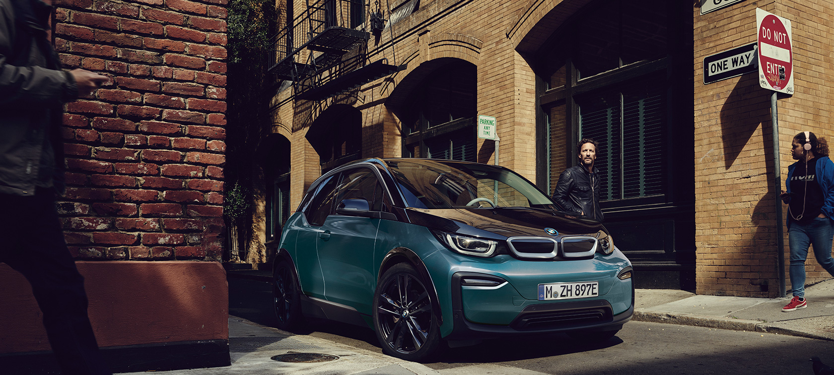 BMW i3 2018 side view driving BMW i3 I01 2018 Fluid Black with BMW i Blue highlights side view driving in urban setting