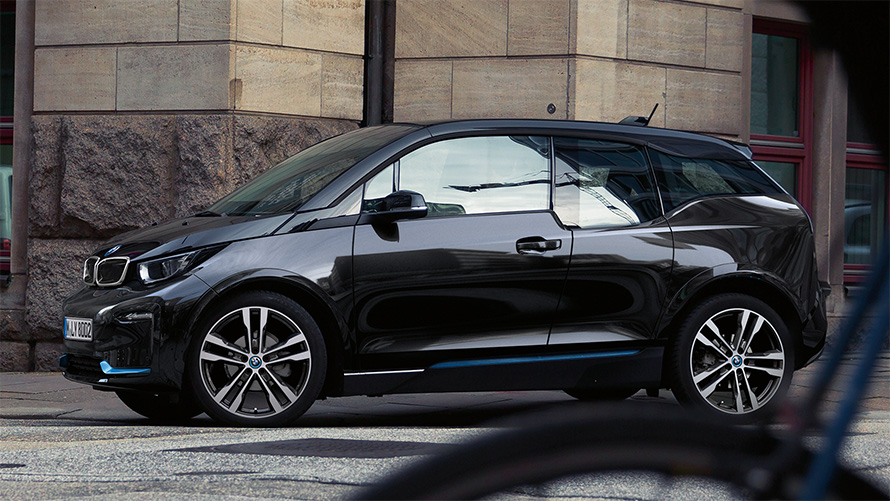 BMW i3s I01 2018 Fluid Black with BMW i Blue highlight side view in urban setting driving