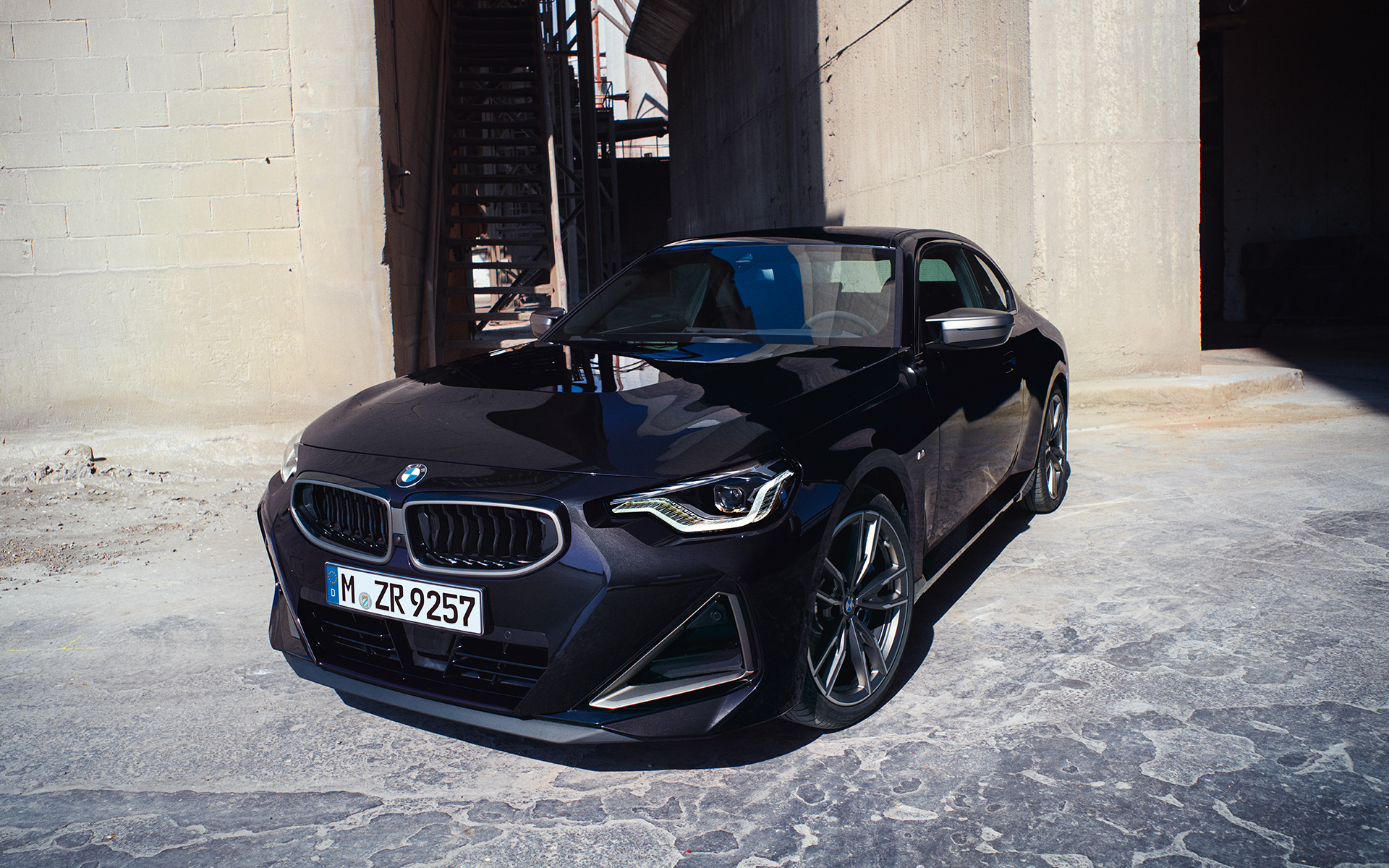 BMW M240i xDrive Coupé G42 2021 Black Sapphire metallic three-quarter front view standing in front of warehouse