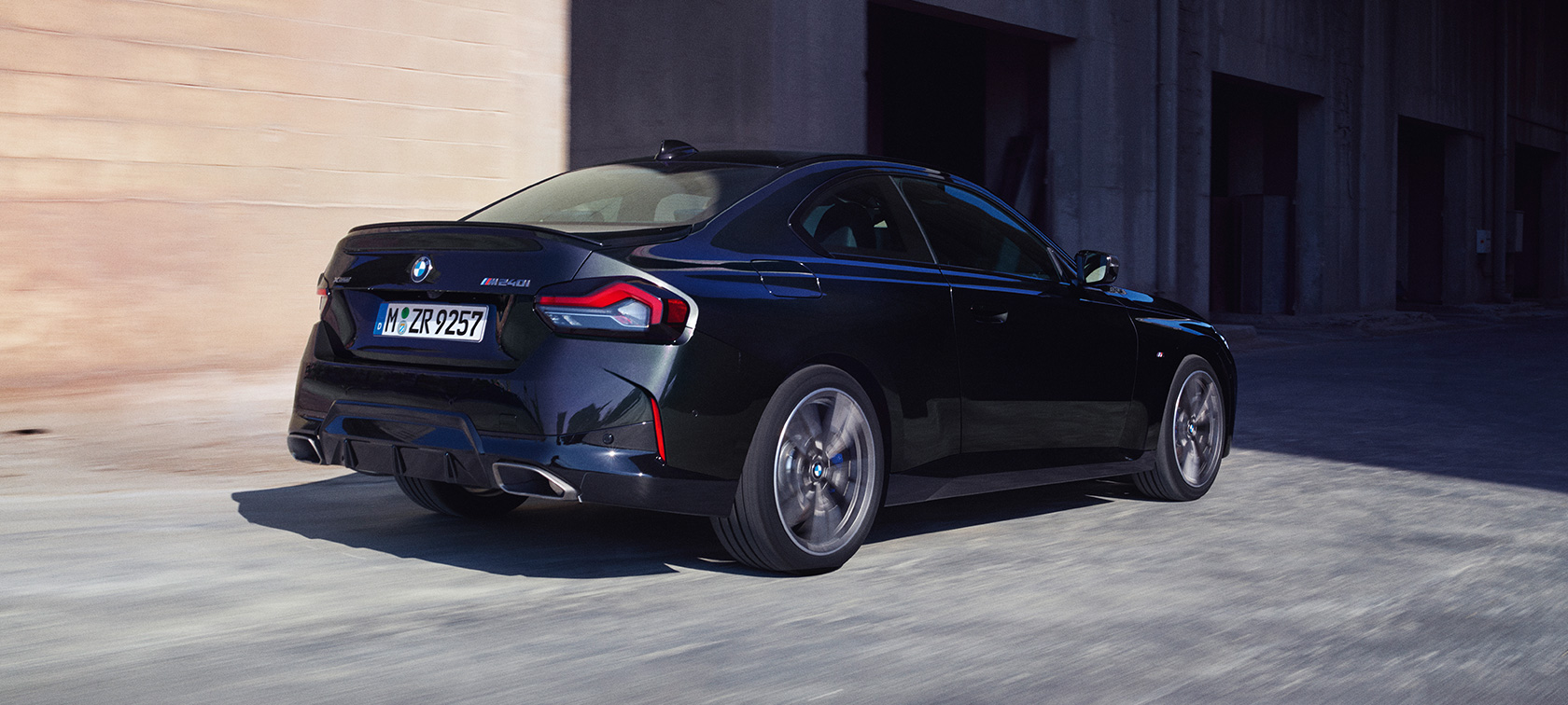 BMW M240i xDrive Coupé G42 2021 Black Sapphire metallic three-quarter rear view driving