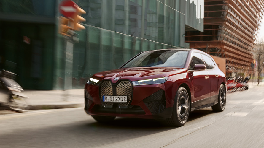 BMW iX3 G08 2021 three-quarter front view driving in front of foggy hilly landscape