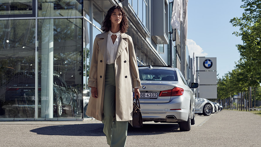 BMW Service Inclusive Woman in front of BMW car dealership